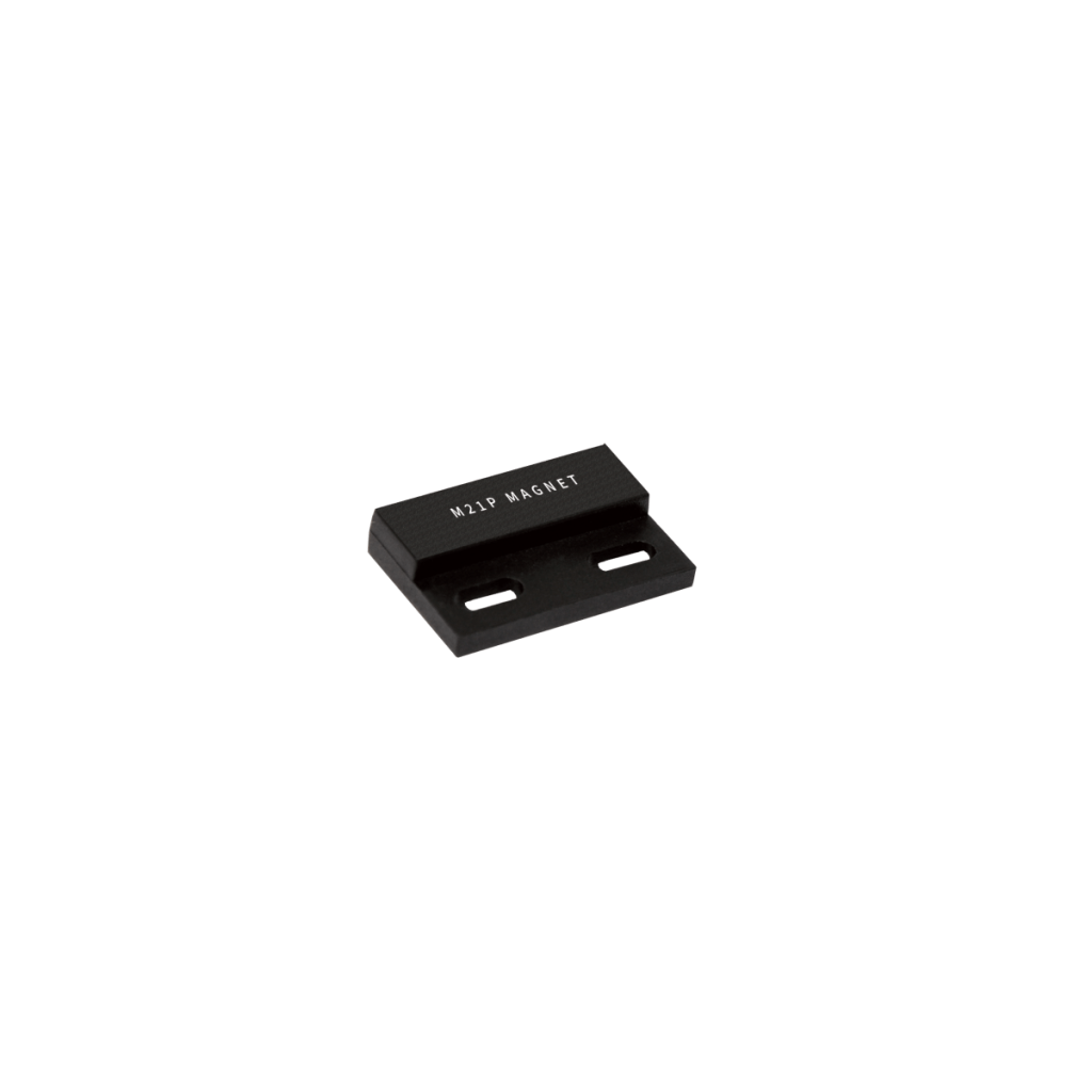A small, black, rectangular metal bracket labeled M21P MAGNET, designed for use with actuators or magnets, features two elongated mounting holes and is displayed against a plain white background. by Standex Detect
